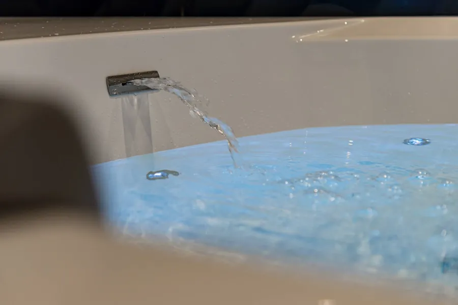 Le filet d’eau qui remplit la baignoire, éclairé en bleu par la chromothérapie